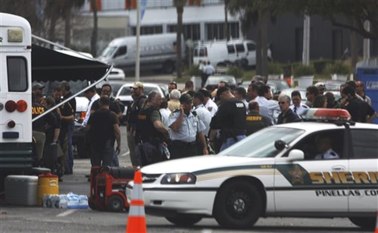 Police officers from various agencies meet at a mobile command center in the parking lot of Tropicana Field in St. Petersburg, Fla., Tuesday, as they search for the man who killed Officer David Crawford, 46. 